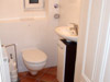 separates WC mit Terrakottafliesen und kleinem Waschbecken
